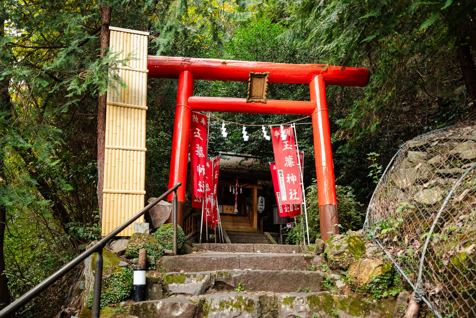 Red torii gate and stone steps leading uphill toward Tamadare Shrine in Tenseien Garden.