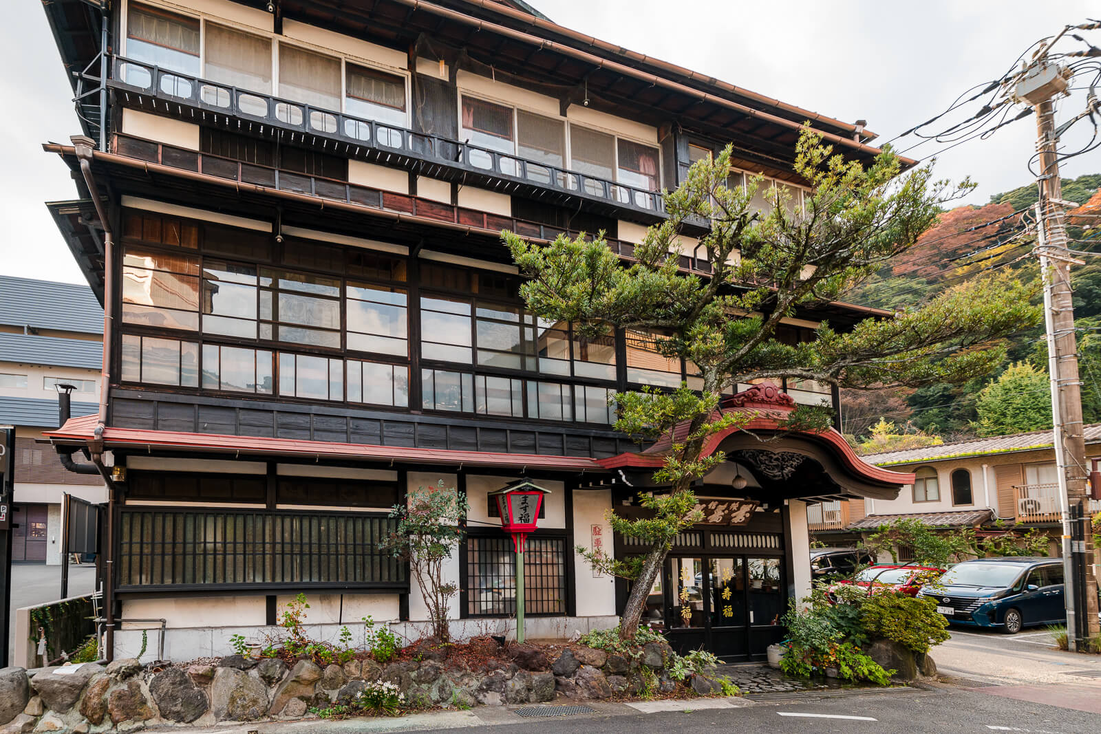 Tenseien hotel exterior in Hakone-Yumoto surrounded by wooded hills showing the first stages of autumn color.