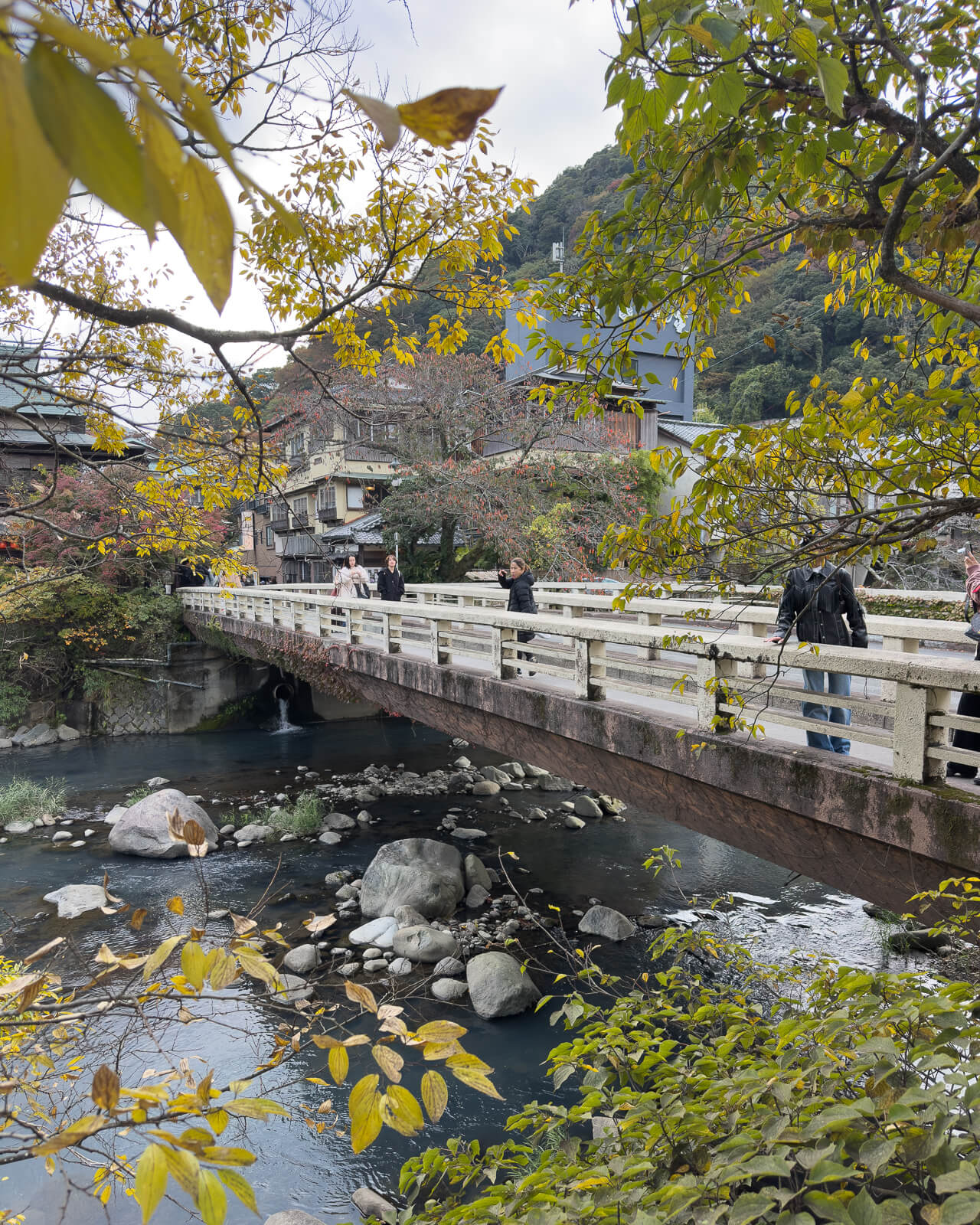 River bridge in Hakone-Yumoto framed by trees beginning to change color during early November.