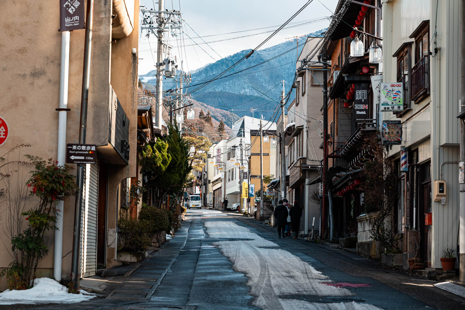 Wider street view in Yudanaka Onsen showing mixed hotel façades