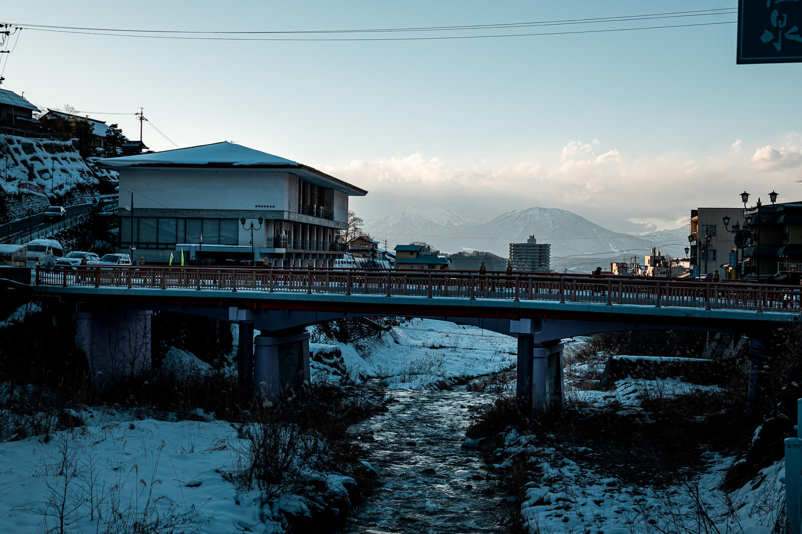 Red pedestrian bridge with mountain backdrop at Shibu Onsen, Yamanouchi