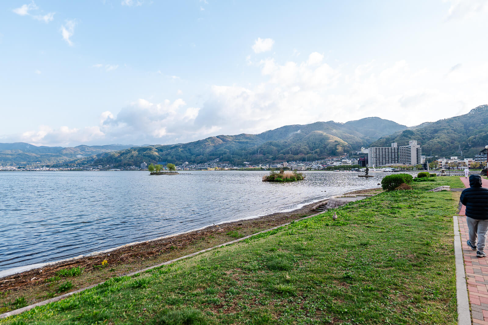 Pedestrian walking along Lake Suwa shoreline