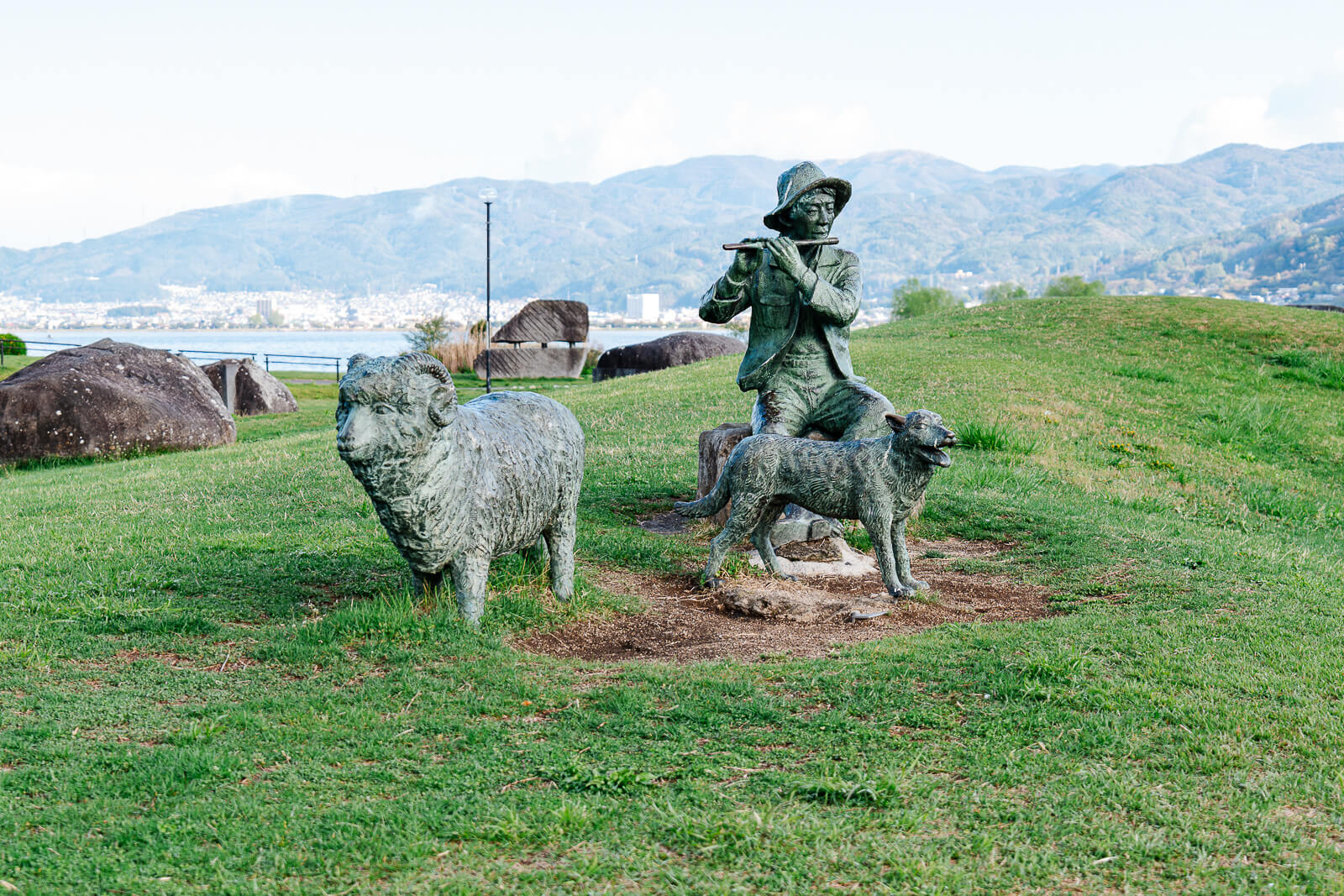 Sculpture figures facing Lake Suwa and surrounding mountains