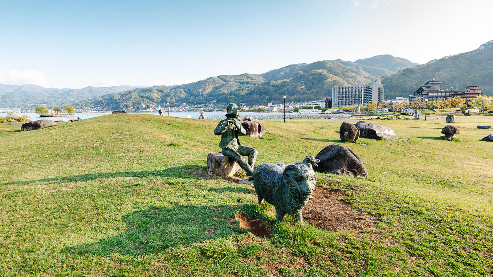 Lakeside park with statue overlooking Lake Suwa and mountains in Nagano, Japan