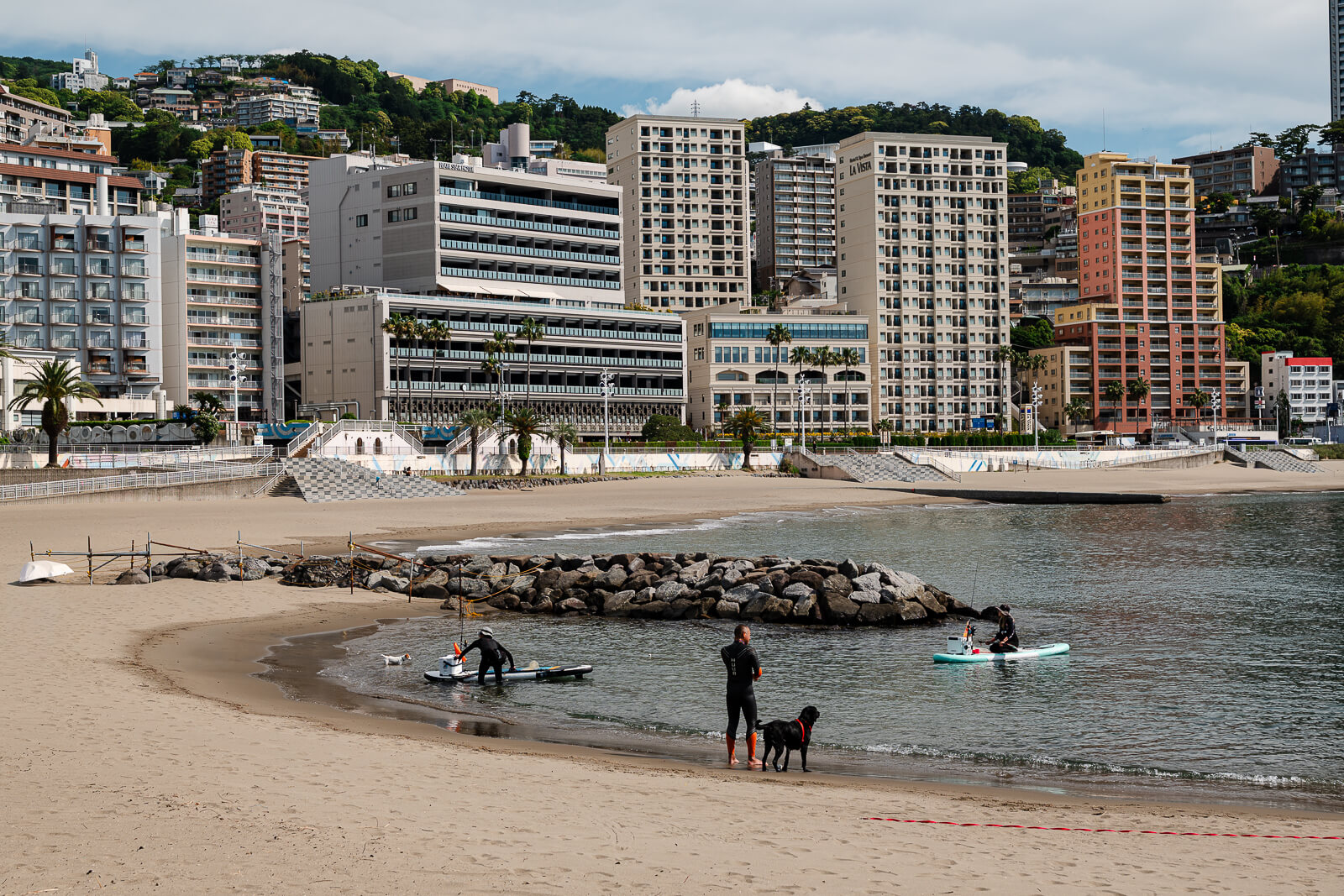 Atami Sun Beach with waterfront hotels behind the shoreline and people near the water.