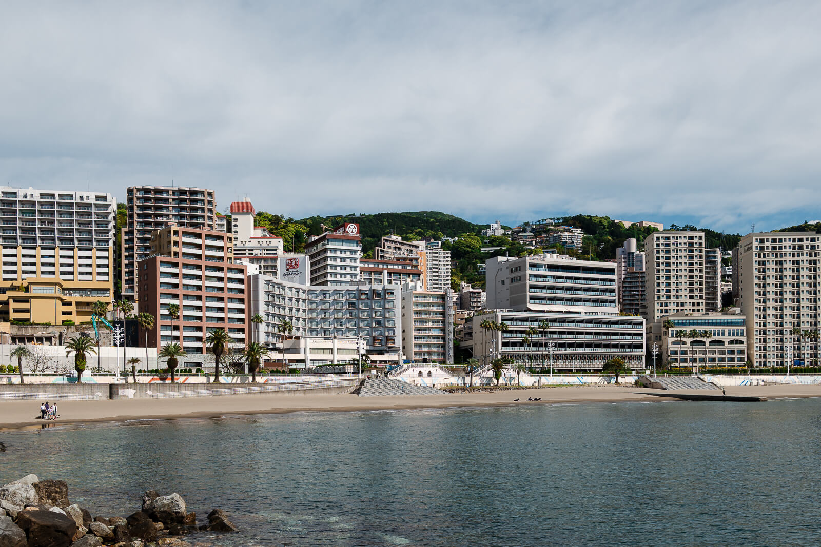 Waterfront hotels along Atami Sun Beach with the shoreline and bay in view.