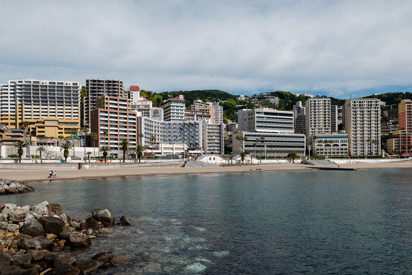 Waterfront hotels along Atami Sun Beach with the shoreline and bay in view.