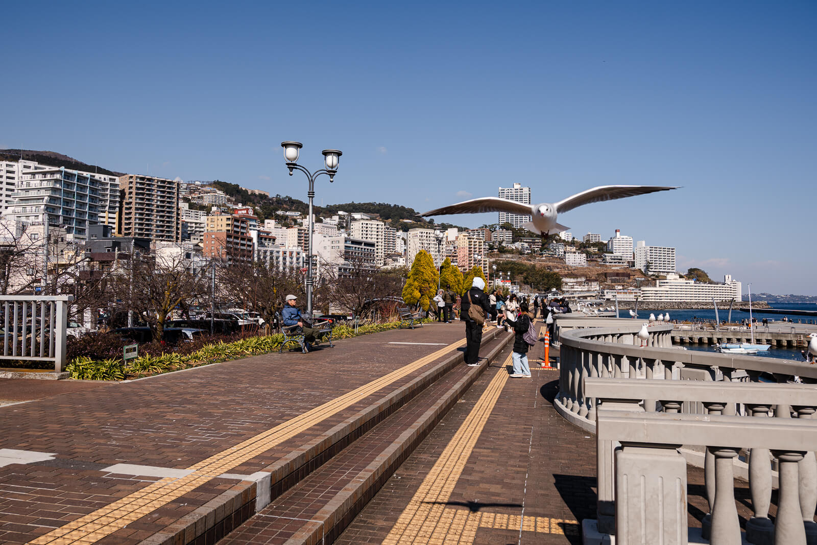 Wooden deck walkway at Atami Water Park facing hillside buildings above the bay