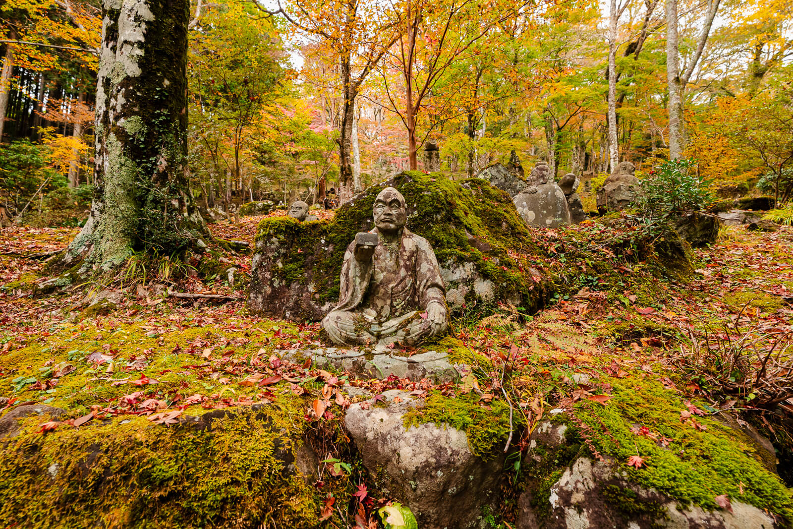 Rakan statues scattered through the autumn forest hillside at Choanji Temple