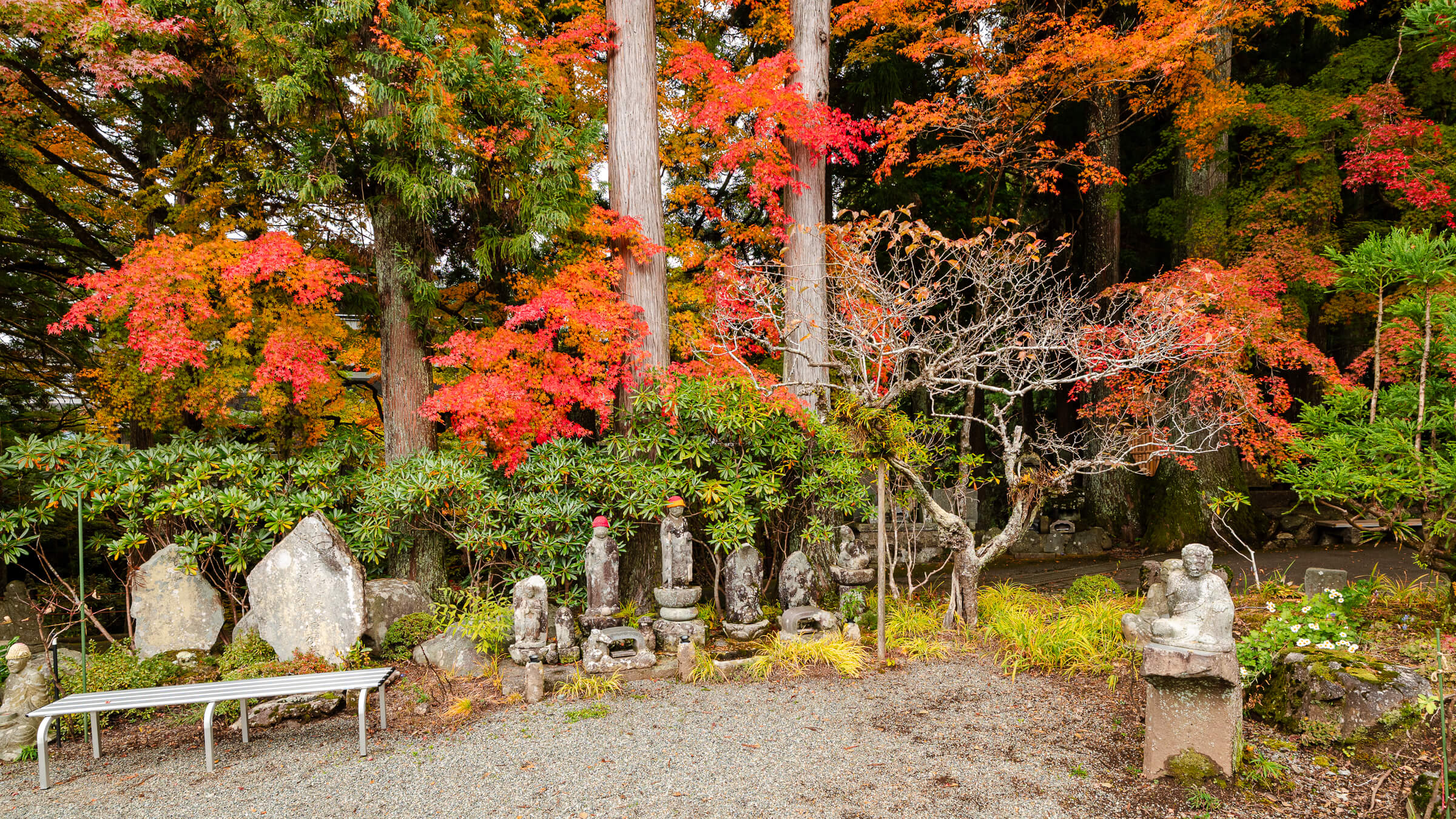 Rakan statues surrounded by vivid red and orange autumn foliage at Chōan-ji Temple in Hakone