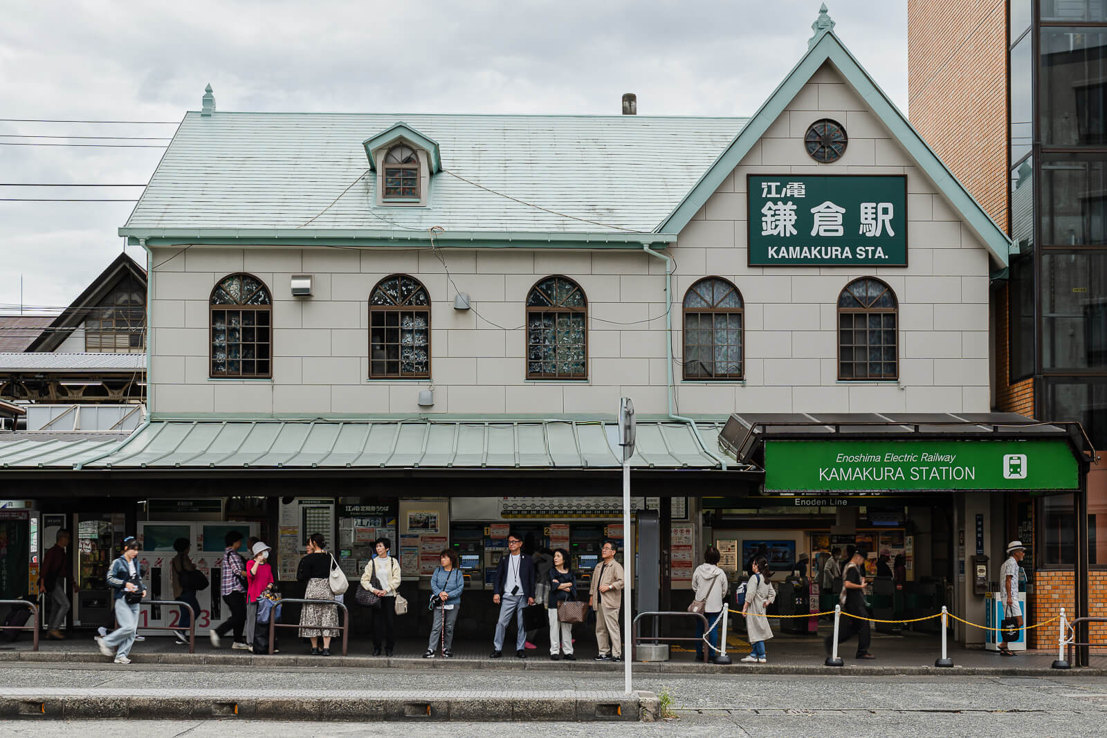 Historic Enoden Kamakura Station building with passengers waiting outside the entrance in central Kamakura