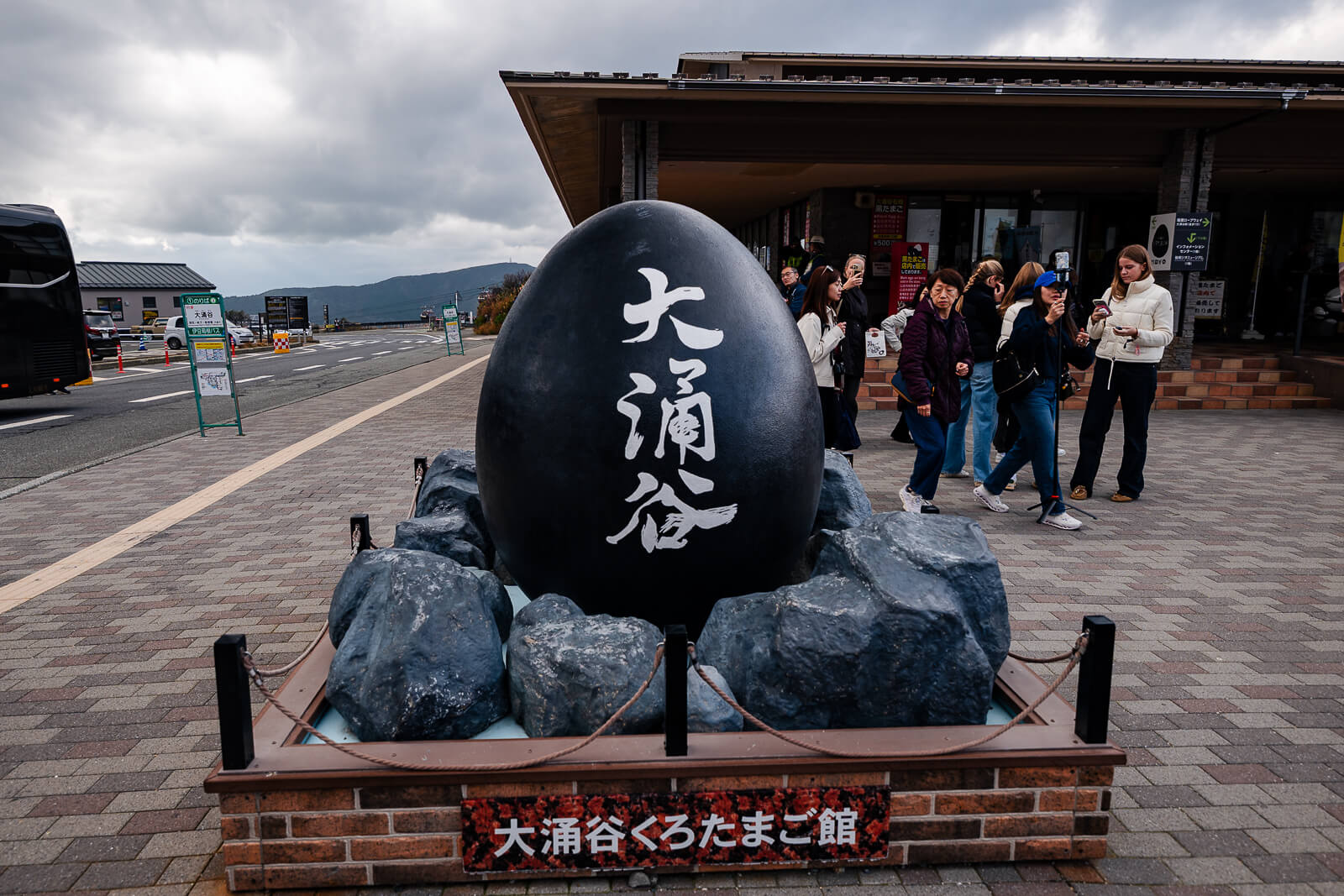 Black egg monument at Owakudani with visitors gathered around the display