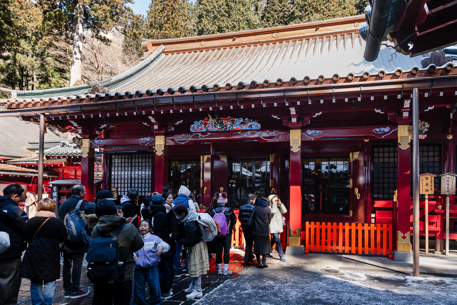 Visitors gathered around red buildings in the main worship precinct at Hakone Shrine in Motohakone