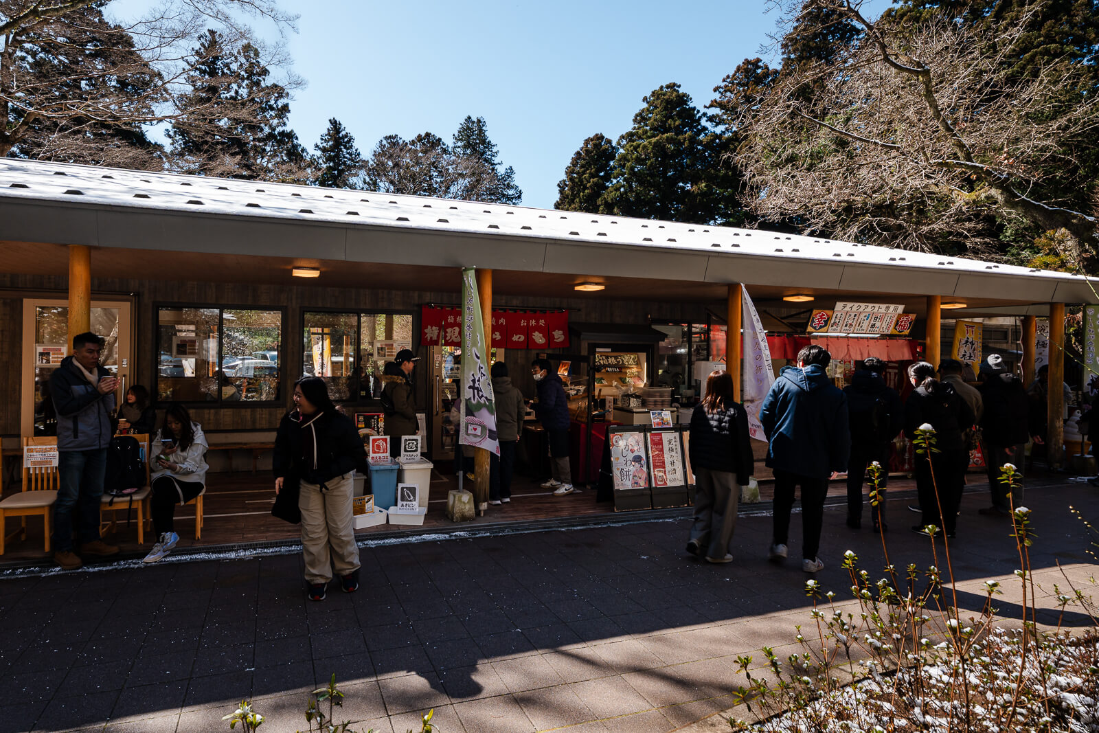 Visitors at a row of reception and shop counters in the grounds of Hakone Shrine in Motohakone