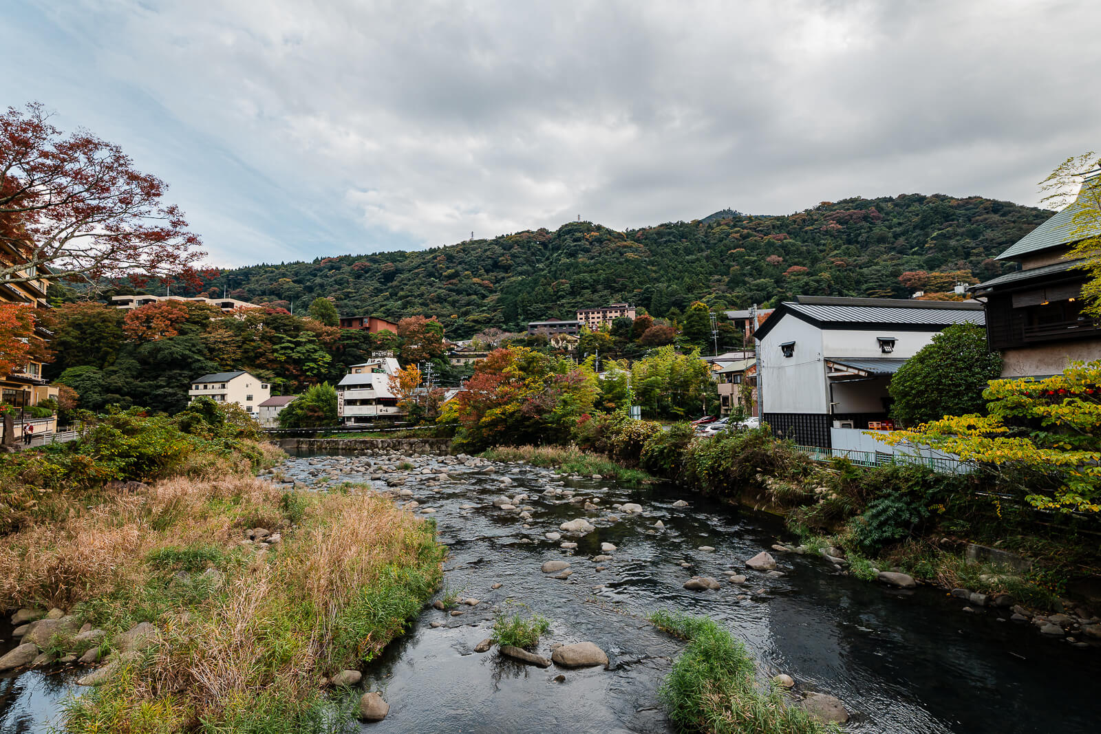 Hayakawa River flowing through Hakone-Yumoto with autumn foliage on the surrounding hills