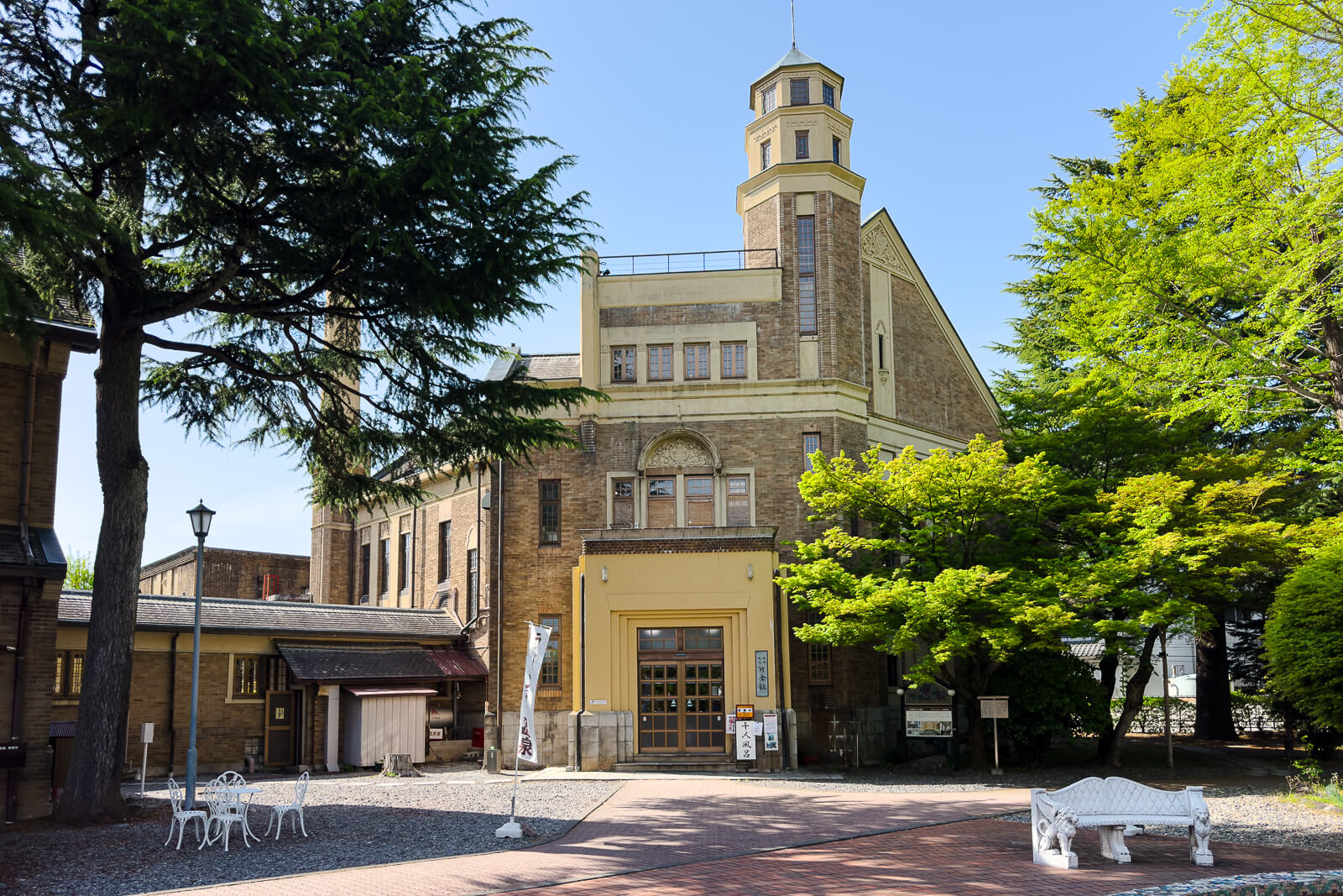 Front exterior of Katakurakan public bathhouse framed by trees in Kamisuwa Onsen