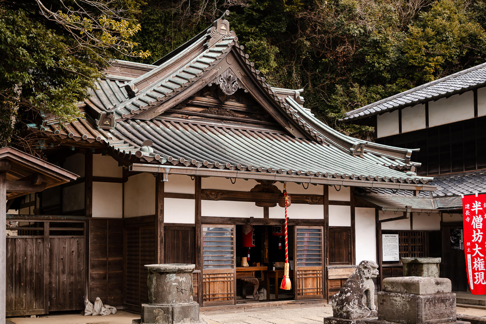 Hansobo Shrine building beside red banners on the hillside above Kencho-ji Temple