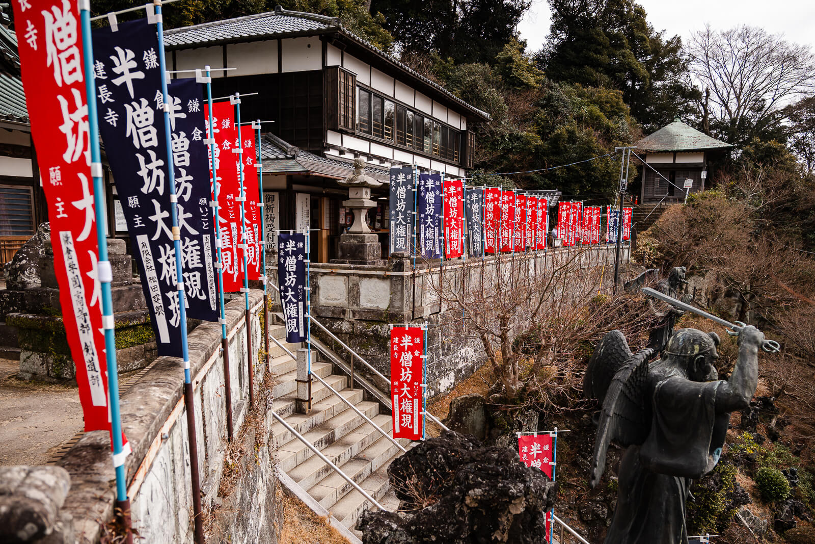 Stone stairway lined with red banners and tengu statues below the Sagami Bay observation deck