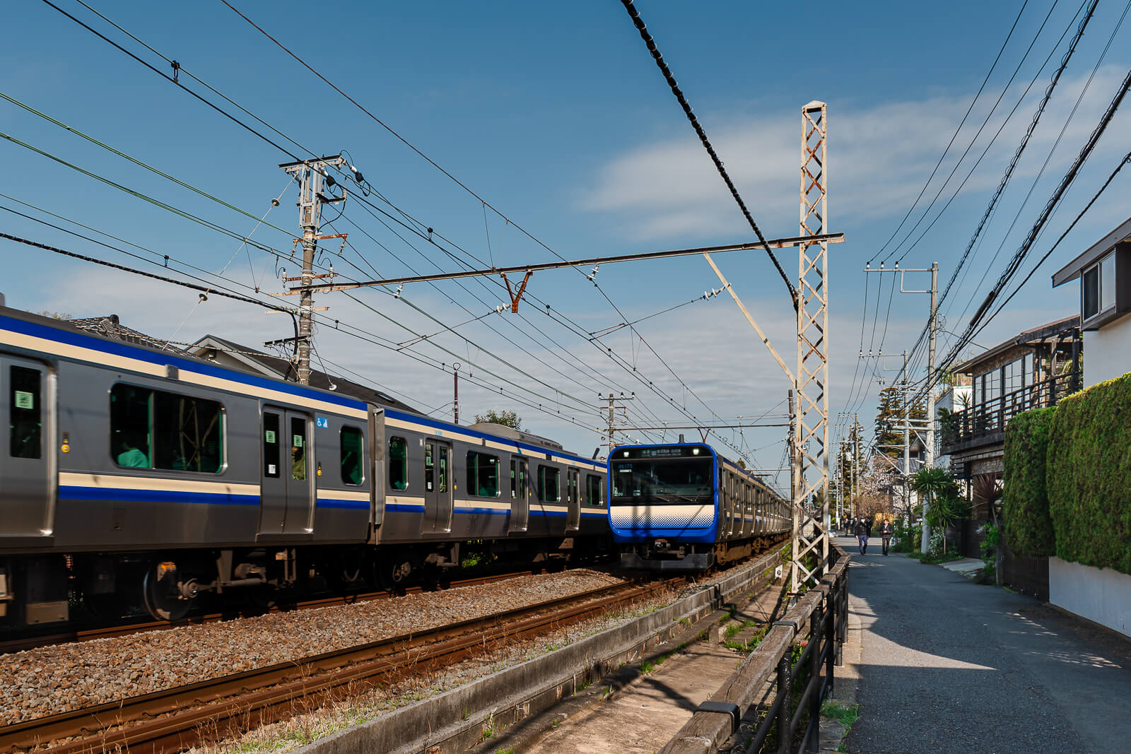 JR Yokosuka Line trains passing a residential street near Kita-Kamakura Station
