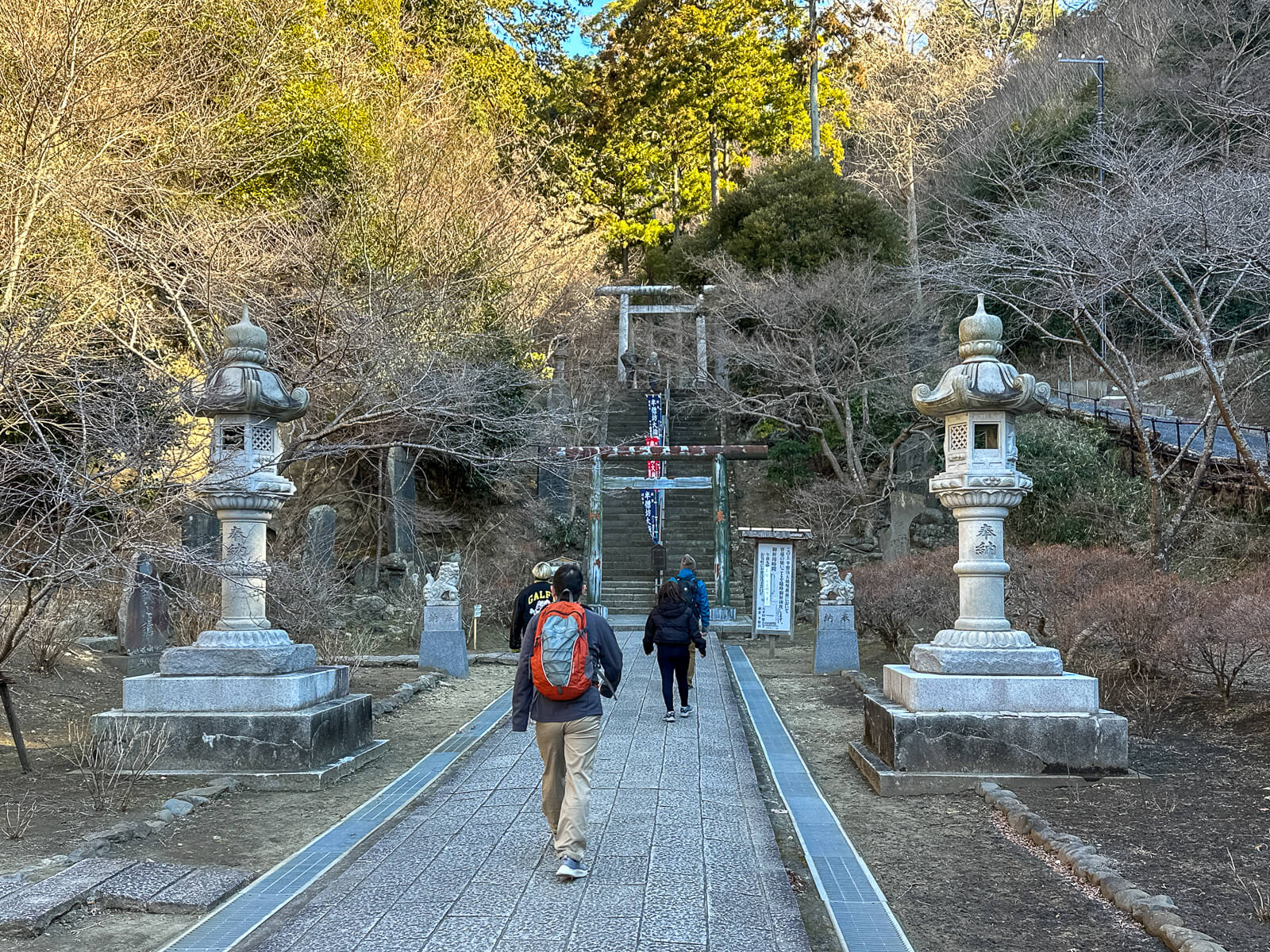 tone path lined with lanterns leading toward Hansōbō through the wooded Kenchō-ji grounds