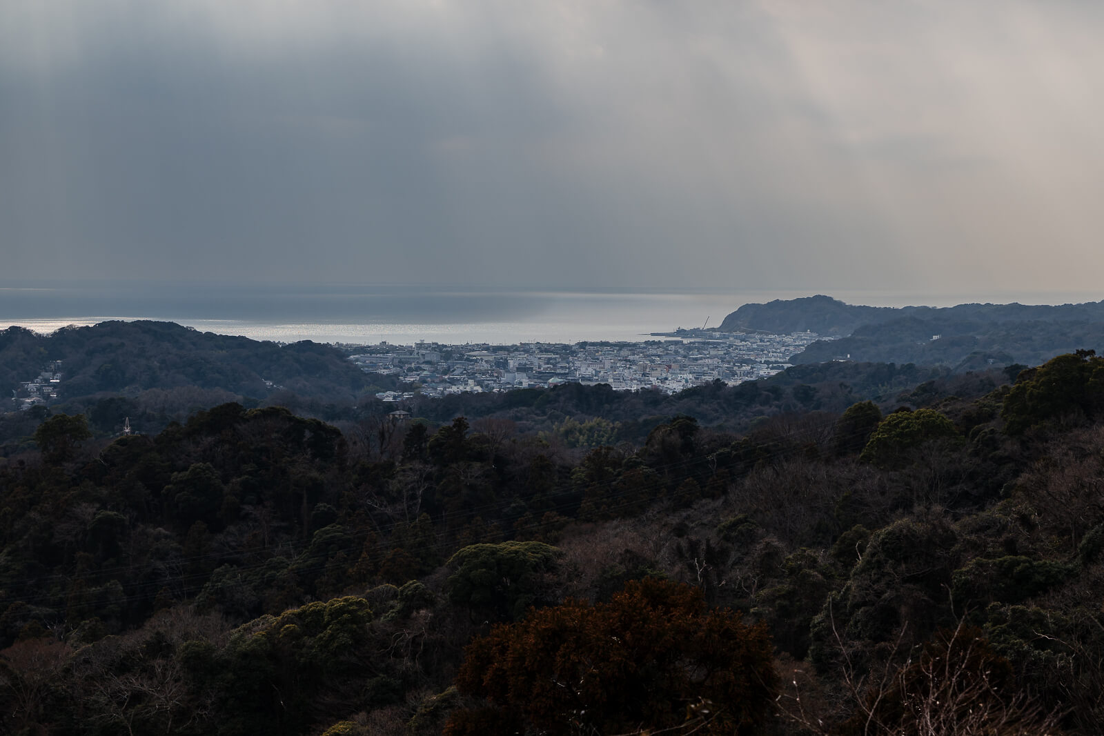 Layered hills and distant coastline viewed from the Ten-en Hiking Course under winter clouds