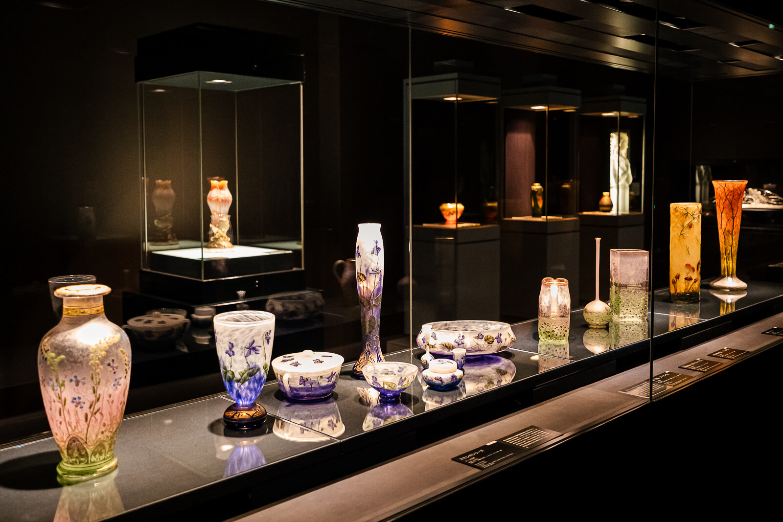 Glass vases and decorative objects displayed in a museum showcase