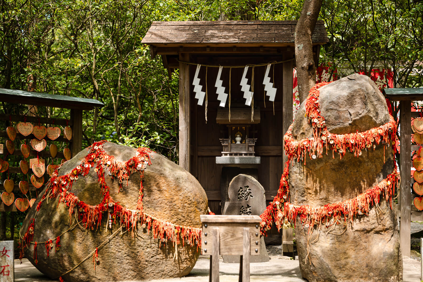 The male and female Enmusubi Stones are linked by red strings beside a small shrine at Kuzuharaoka Shrine