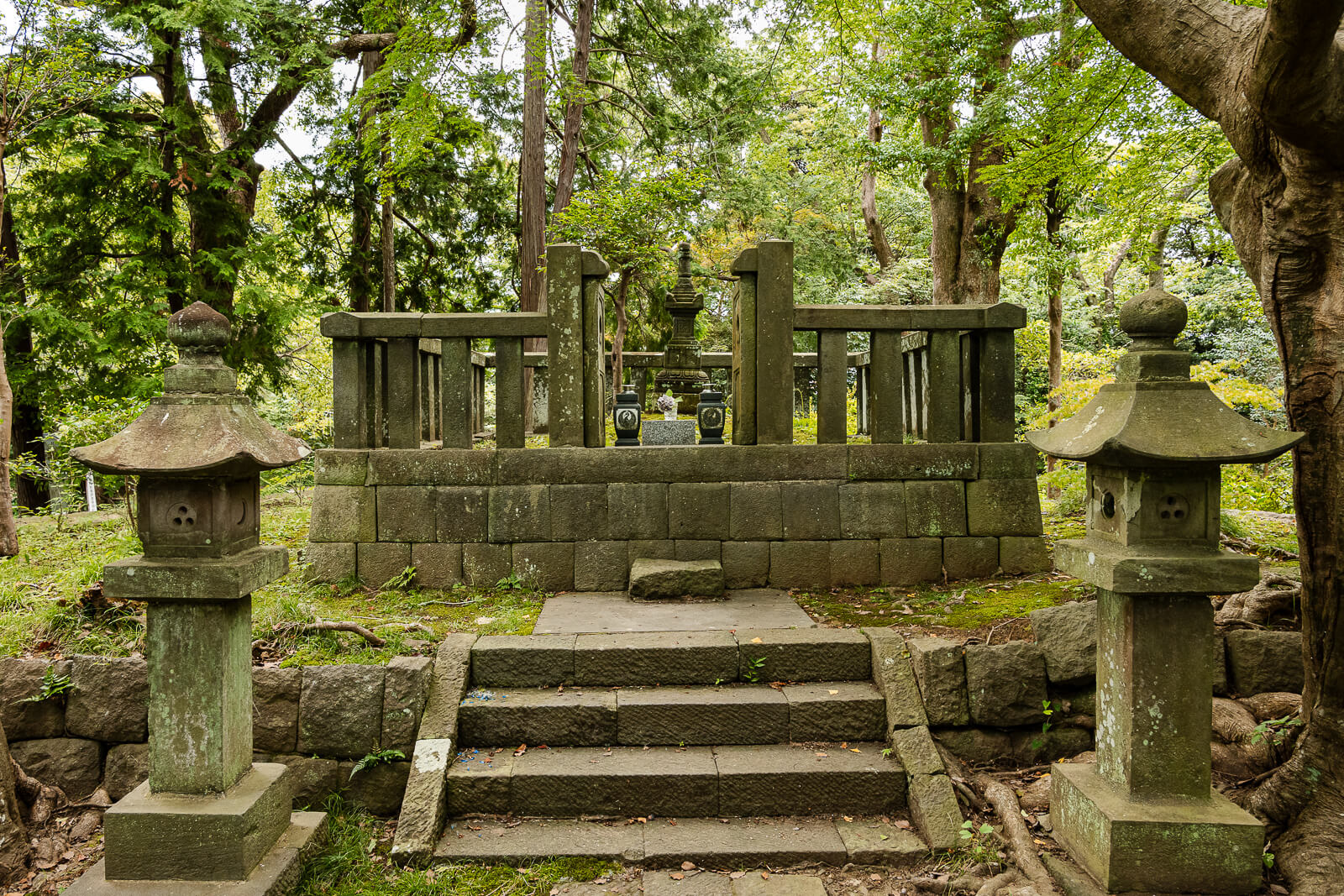Stone lanterns and a railing surround the hōkyōintō marking Hino Toshimoto’s grave in Kamakura