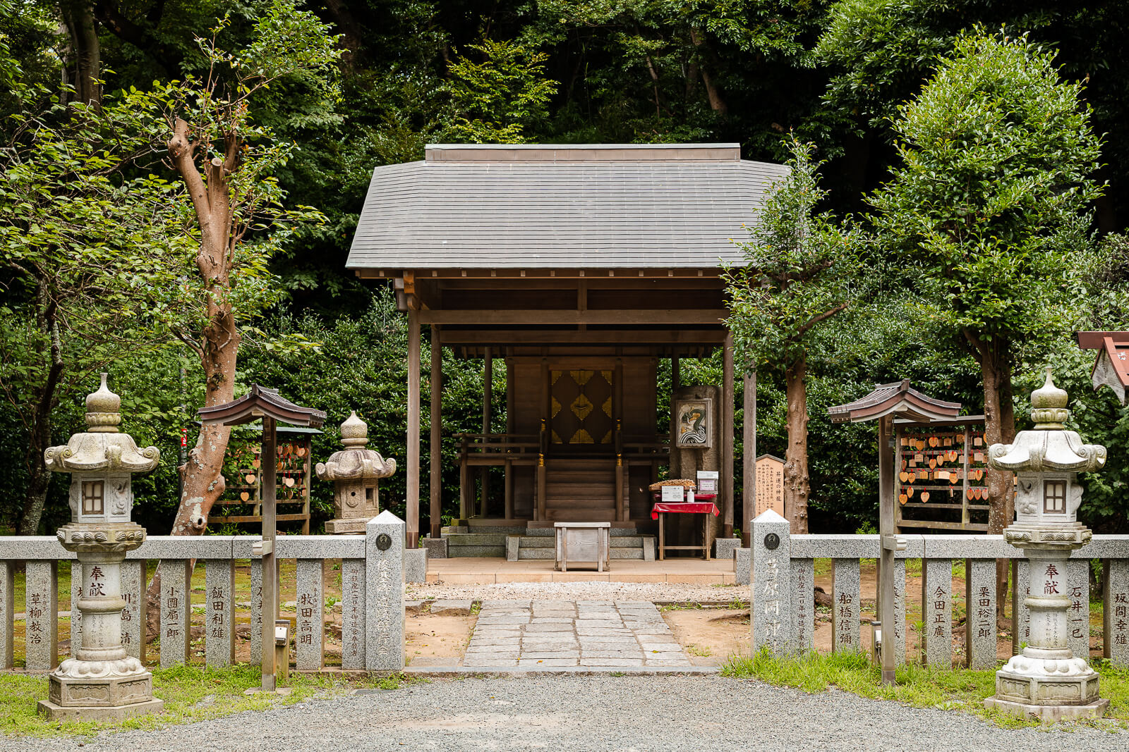 The main shrine building at Kuzuharaoka Shrine stands behind stone lanterns and a low stone enclosure