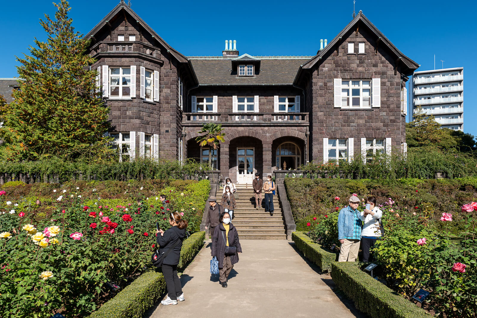 The Western-style mansion at Kyu-Furukawa Gardens rises above a lawn and flower beds under a clear blue autumn sky.