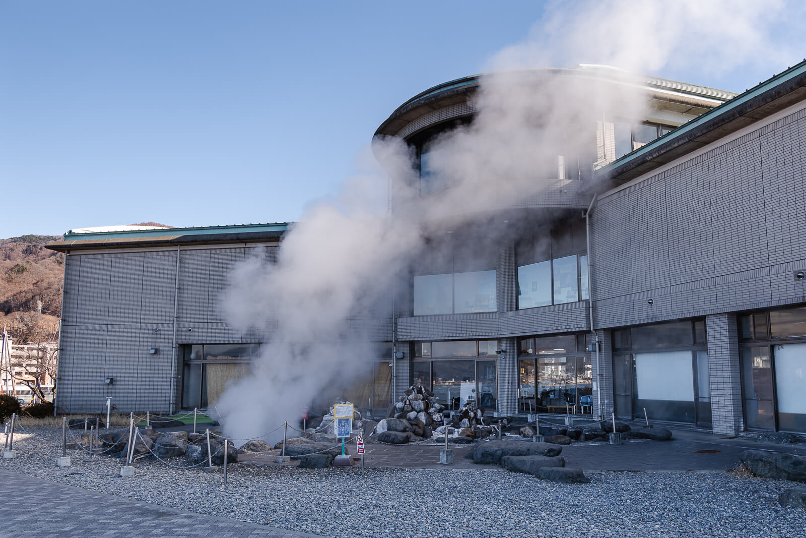 Steam plume rising beside the Lake Suwa Geyser Center building