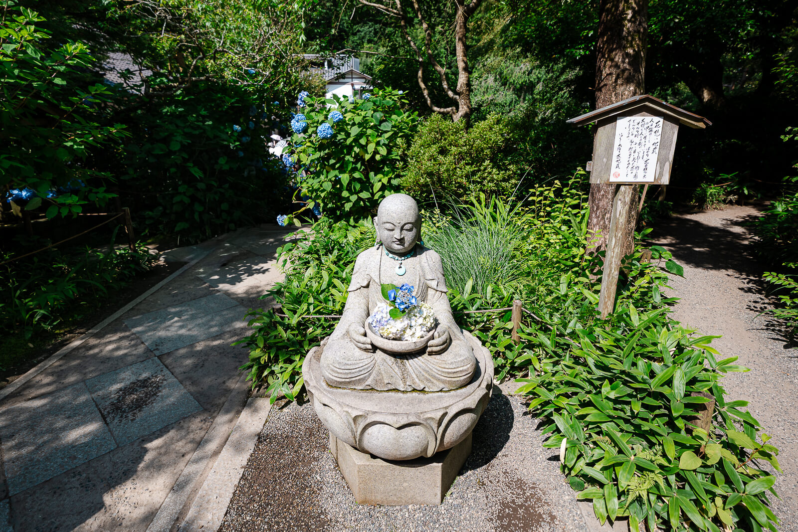 Flower-adorned Jizo statue along a path at Meigetsu-in Temple in Kita-Kamakura