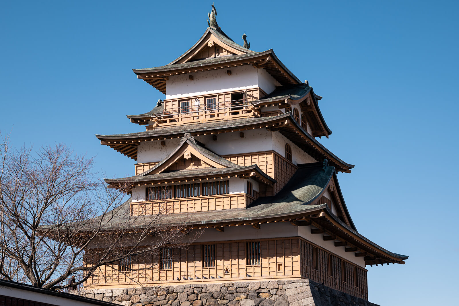 Takashima Castle keep rising above stone walls beside Lake Suwa