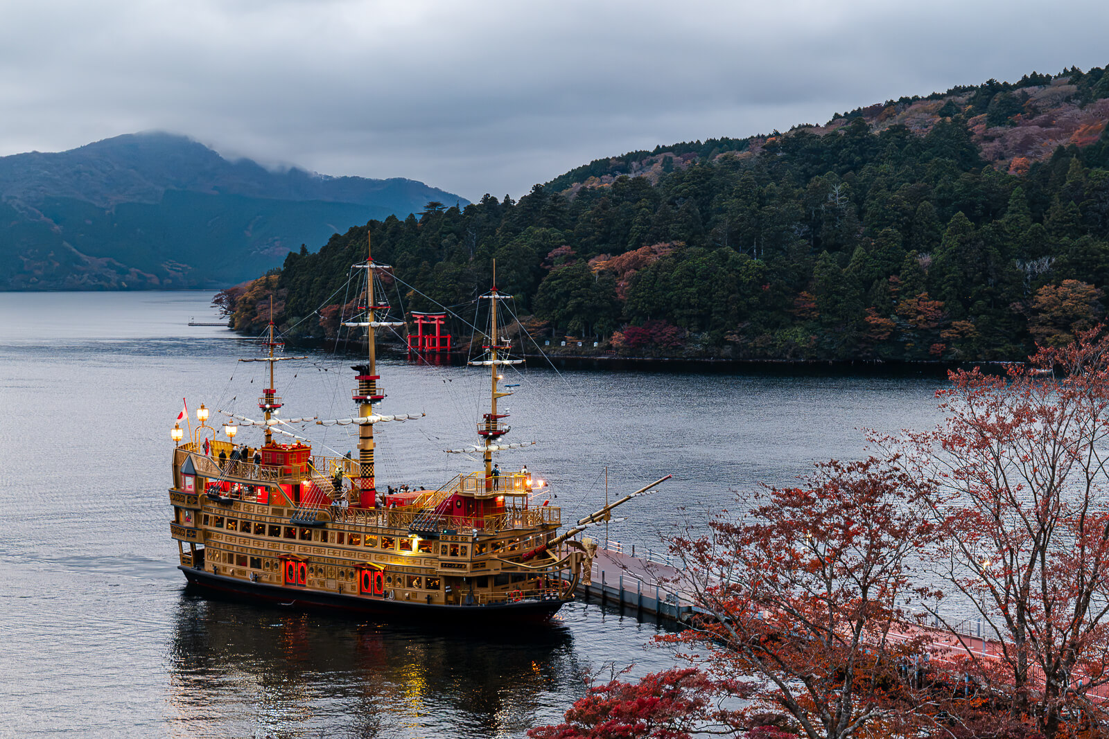 Lake Ashi sightseeing ship viewed from Narukawa Art Museum with autumn hills beyond
