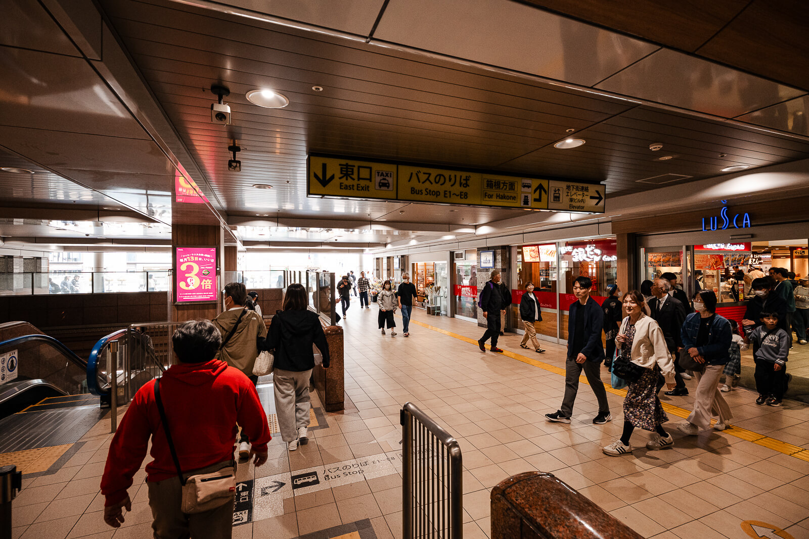 Travelers moving through a shopping and restaurant corridor inside Odawara Station