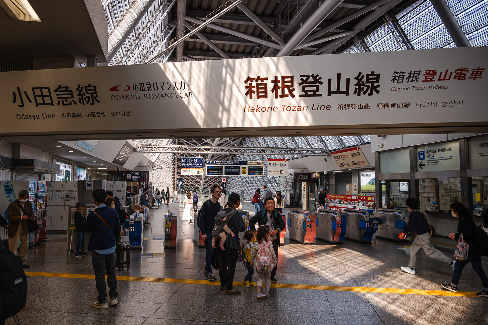 Travelers standing beneath Hakone Tozan Line signage inside Odawara Station