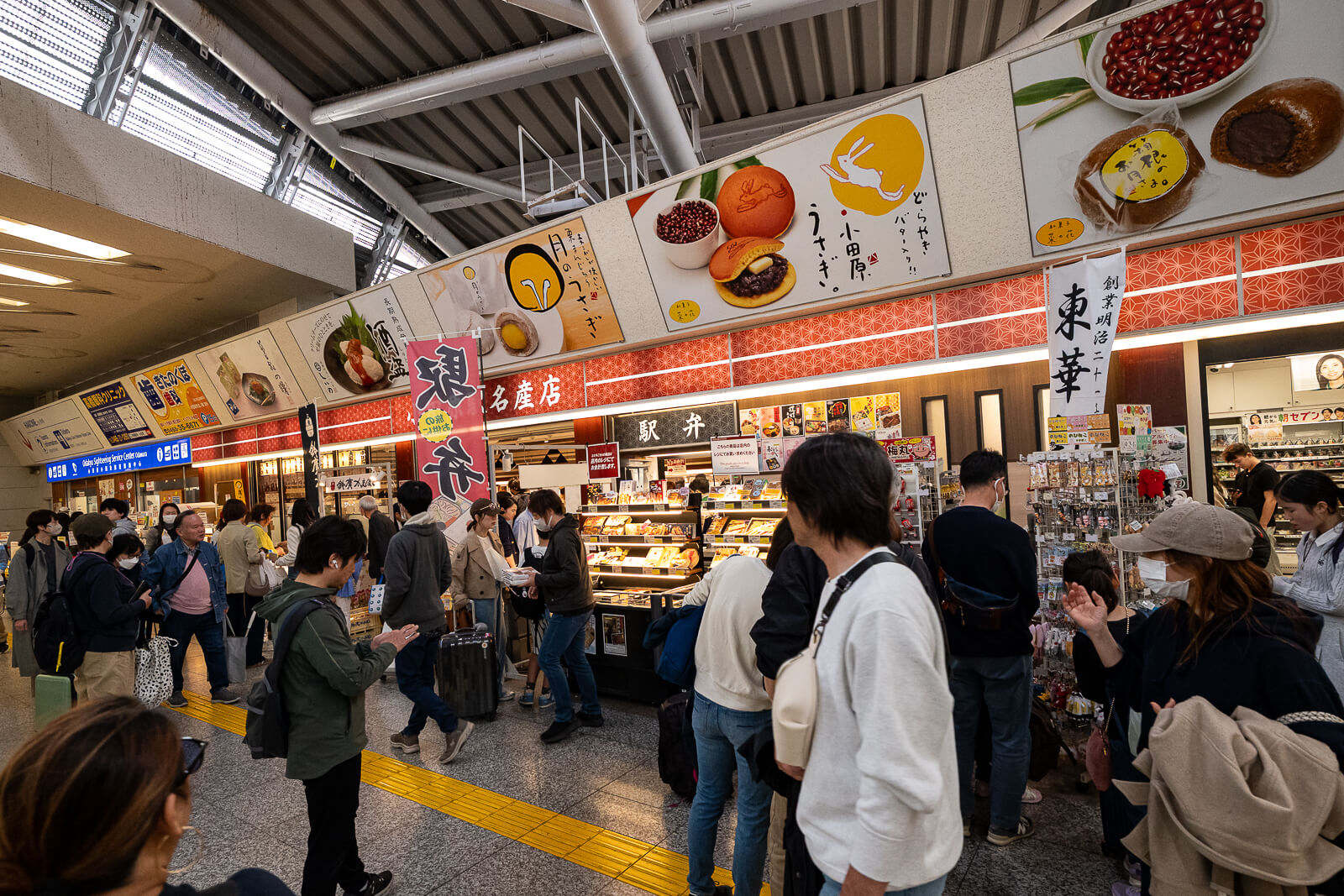 Travelers moving through food and shopping areas inside Odawara Station