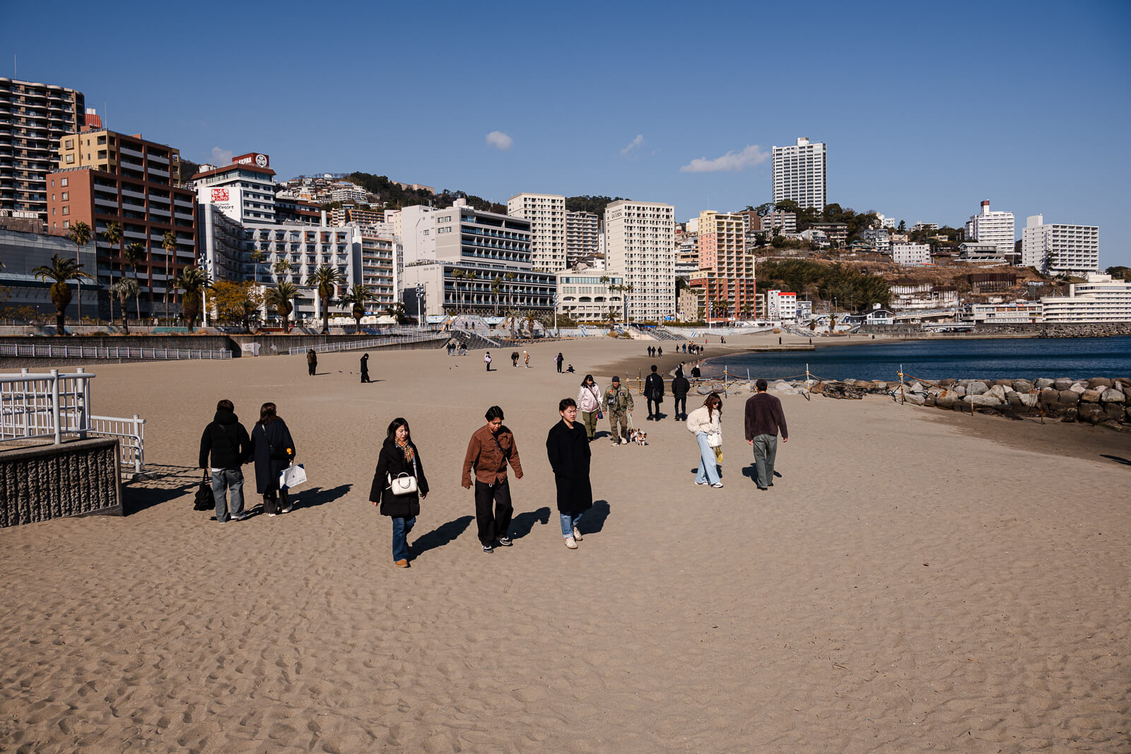 People walking along the promenade behind Atami Sun Beach