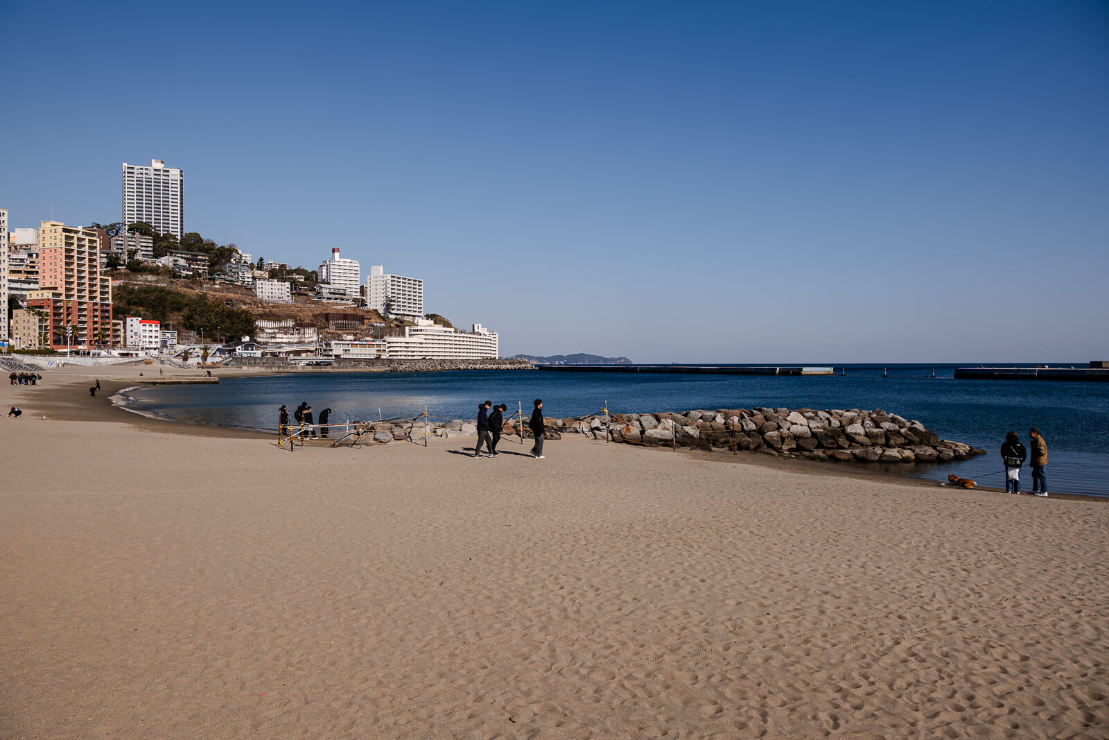 Curved shoreline of Atami Sun Beach along Atami Bay with marina visible