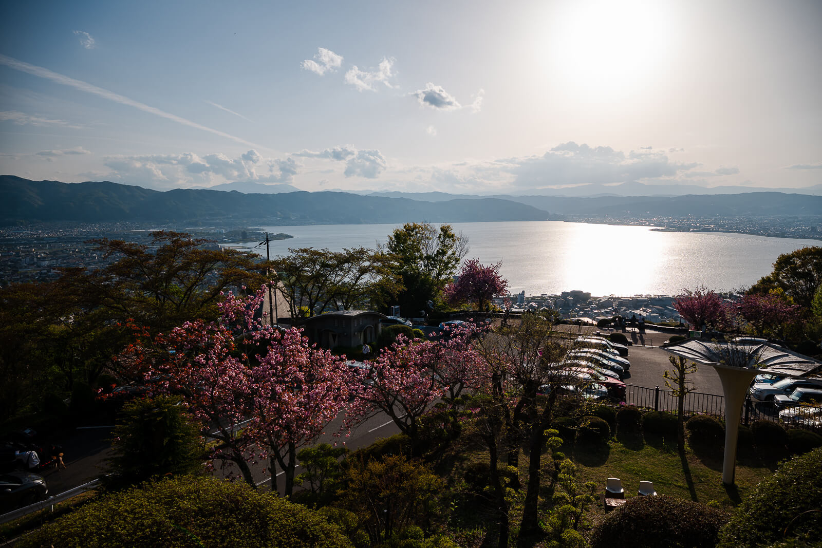 Lake Suwa viewed from Tateishi Park with spring blossoms and afternoon sunlight