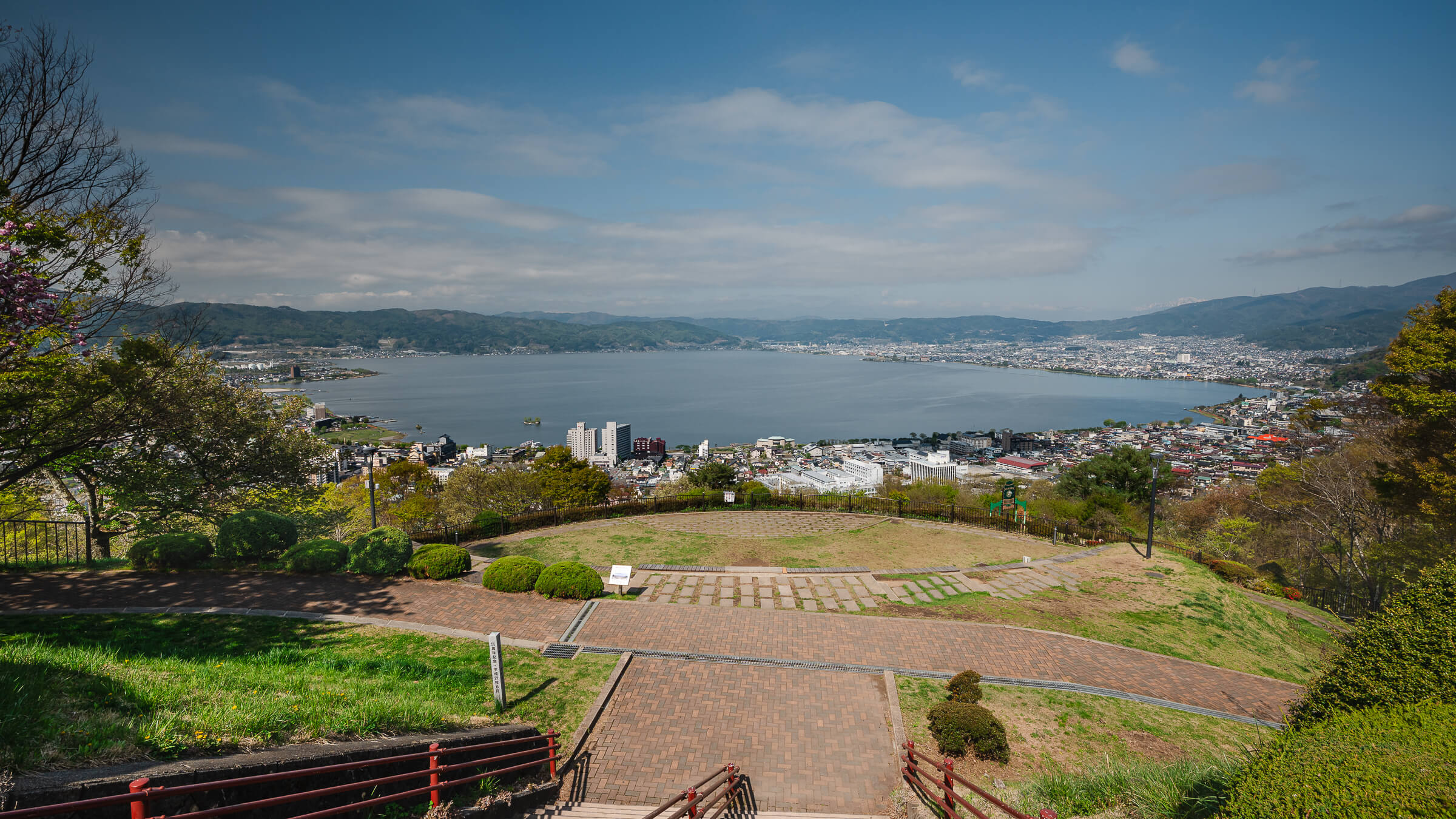 View of Lake Suwa from Tateishi Park with spring foliage and cherry blossoms in late April
